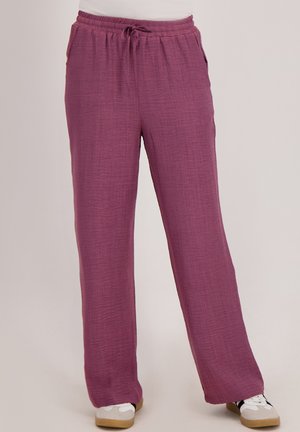 Losse, pruimkleurige broek met een verstelbare tailleband, gedragen met witte sneakers, getoond op eenstaande persoon.