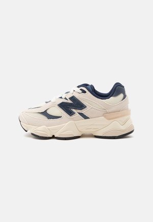 Low-Top Sport-Sneaker in Beige und Navy mit dicker Sohle, Mesh- und Velours-Paneelen und einem großen navyfarbenen Logo an der Seite.