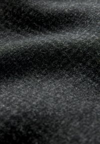 Čierny plstený materiál so soft, textúrovaným povrchom. Obsahuje jemné sivé vlákna prepletené dohromady, čím vytvára bohatý, hustý vzhľad.