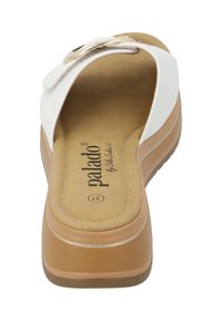 White flip-flop sandal with a slightly raised sole, tan padded insole, and silver accent on the strap. Text branded on the insole.