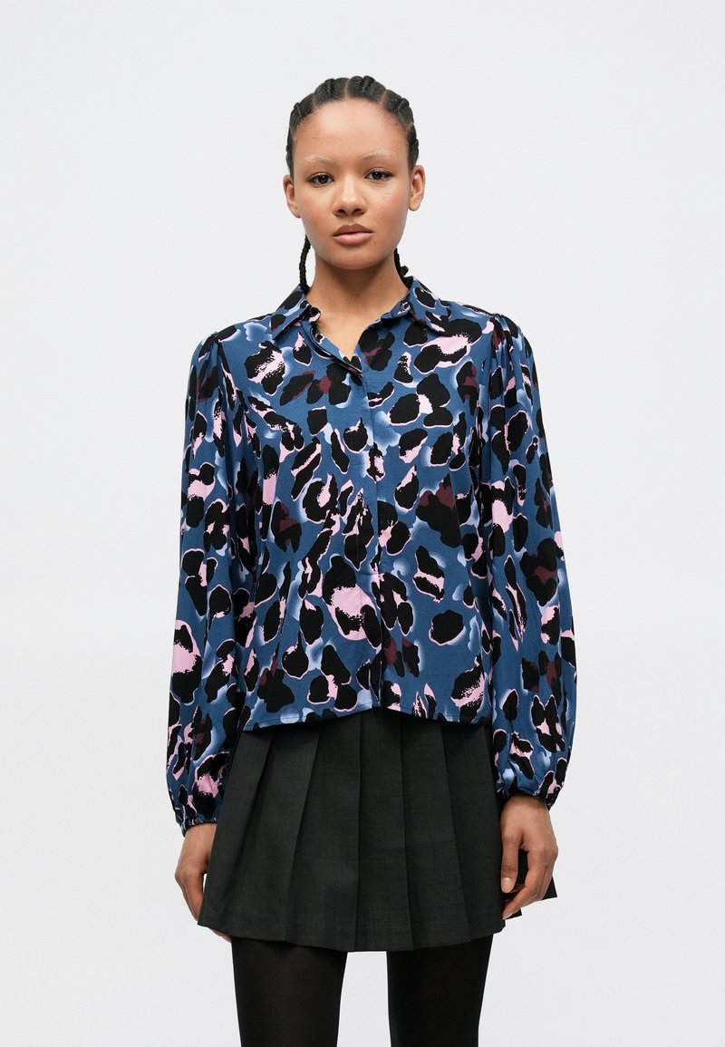 Bluse med lange ermer i blått satinmateriale, med et flerfarget leopardmønster. Knappelukking med klassisk krage og rynkede ermekanter.