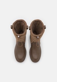 Bottes d'hiver marron avec tige matelassée, finition en cuir texturé et doublure en tissu. Dotées de languettes de traction et d'accents de quincaillerie décoratifs.