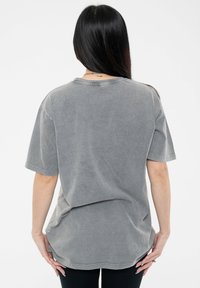Gray oversized cotton t-shirt with a relaxed fit, short sleeves, and a round neckline. Features a soft, faded texture and side slits.