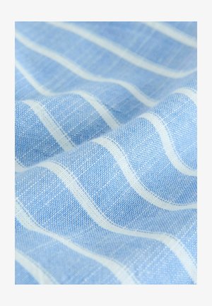 Tissu bleu clair avec une surface texturée, présentant des rayures blanches ondulées. Le tissage montre des épaisseurs variées, créant un intérêt visuel.