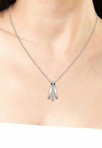 Collana in argento con due pezzi di metallo allungati e lucidi disposti a forma di V, decorata con una fila di cristalli trasparenti al centro.