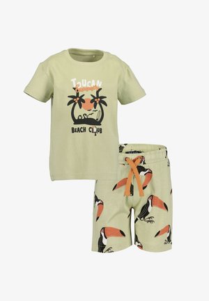 Lys grøn bomulds t-shirt med tucan grafik og tekst, parret med matchende shorts med flere tucaner, sorte, orange og beige accenter.