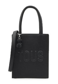 Bolso tote de cuero negro texturizado con logo "TOUS" en relieve, asas cortas y un charm de oso desmontable. Forma cuadrada compacta.