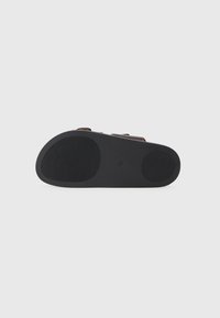 Μαύρη καουτσούκ σόλα σανδαλιού με υφή για καλύτερη πρόσφυση, διαθέτει δύο ρυθμιζόμενες καφέ λωρίδες. Λείος φινίρισμα με στρογγυλή μύτη.