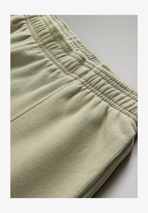 Kerged rohelised dressipüksid, millel on elastne vöökoht, tekstuuriga kangas ja nähtavad õmblused õmblustel.