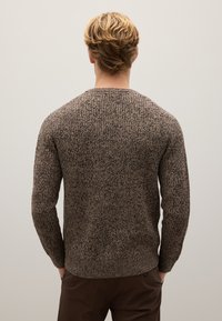 Maglione a maglia marrone con texture, maniche lunghe, polsini e orlo a coste. Presenta un collo a giro e una vestibilità leggermente ampia per il massimo comfort.
