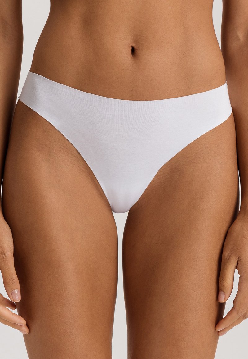 String en coton blanc avec une finition lisse, un design minimaliste et une taille basse pour une silhouette épurée.