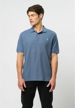 Šviesiai mėlynos spalvos polo marškiniai, pagaminti iš tekstūruotos medžiagos, su trimis mygtukais priekyje ir siuvinėtu logotipu kairėje krūtinės pusėje.
