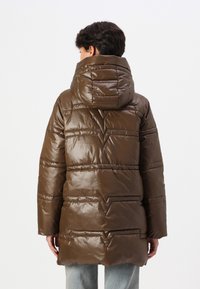 Jachetă puffer marron cu finisaj lucios, glugă și detalii de cusătură în formă de zigzag. Mâneci lungi și croială până la șold. Vedere din spate afișată.