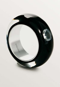 Anillo de resina negra y transparente con un gran acento de gema ovalada, superficie lisa y grabado interior con el nombre de la marca.