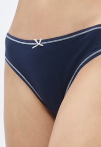 Σκούρο μπλε εσώρουχο τύπου σλιπ με απαλό υφή, με γκρι ανοιχτό λεπτομέρειες και μικρό λευκό φιόγκο στη μέση.