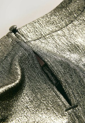Skinnende metallisk stof med en struktureret finish, der har en knapdetalje og en lille åbning. Farven er en blanding af sølv og mørkegrå.