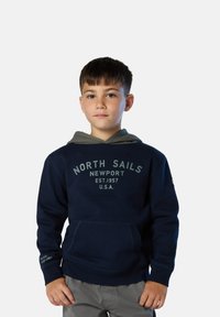 Sudadera azul marino con capucha gris, gran bolsillo delantero y estampado de "North Sails Newport". Presenta puños y dobladillo de canalé, material de algodón.
