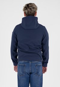 Navy-Hoodie mit weichem Material, ausgestattet mit einer vorderen Kängurutasche und einer verstellbaren Kapuze, kombiniert mit blauen Jeans.