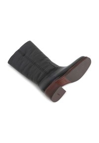 Botte en cuir noir jusqu'au genou avec une texture lisse, des coutures décoratives et un talon en bloc marron ; équipée d'une semelle en caoutchouc avec une adhérence à motifs.