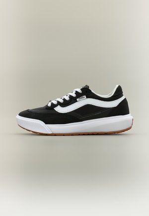 Ασπρόμαυρο παπούτσι Vans χαμηλής κορυφής με λευκά κορδόνια, λευκή πλαϊνή ρίγα και παχιά λευκή σόλα με καφέ πέλμα.