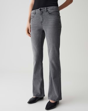 Jeans flare en denim gris avec une taille mi-haute, cinq poches, des détails de couture subtils et une texture lisse. Portés avec des chaussures à talons noires.