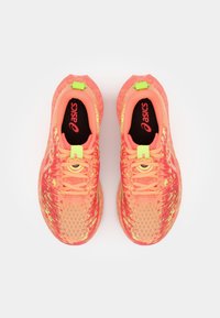 Chaussures de sport avec une tige en maille respirante dans des teintes vives de rose et de jaune, dotées d'accents réfléchissants et de semelles intérieures noires.