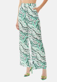 Wide-leg trousers in a light fabric, featuring a green and black leaf pattern on a white background. Mid-rise with side pockets.