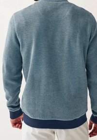 Sweat-shirt texturé bleu à manches longues, col rond et ourlet côtelé bleu marine. Vue de dos montrant un motif chevrons subtil.