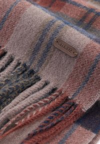 Ullscarf i nyanser av lila, rosa och blå med ett rutig mönster. Har fransar och en läderetikett med präglad text "ombre."