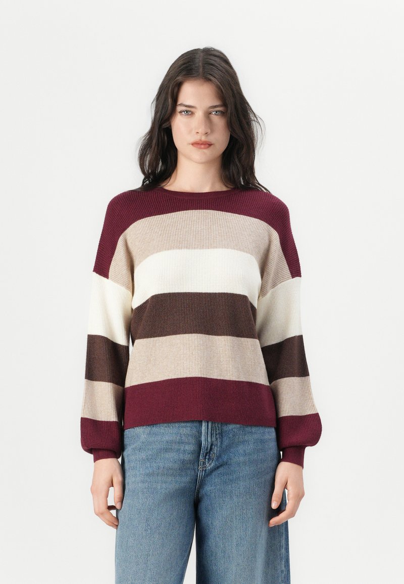 Pull en tricot avec de larges rayures horizontales en bordeaux, crème et marron. Présente un col rond et une coupe décontractée avec des poignets côtelés.