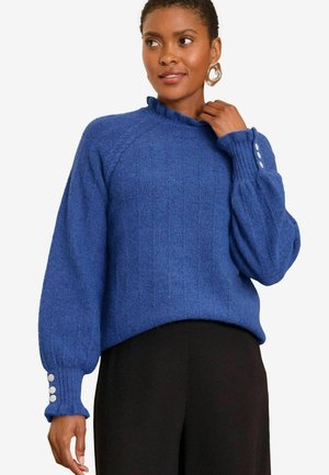 Pull en tricot bleu avec une texture côtelée, présentant un col volanté et des accents de boutons sur les manches. Coupe décontractée.