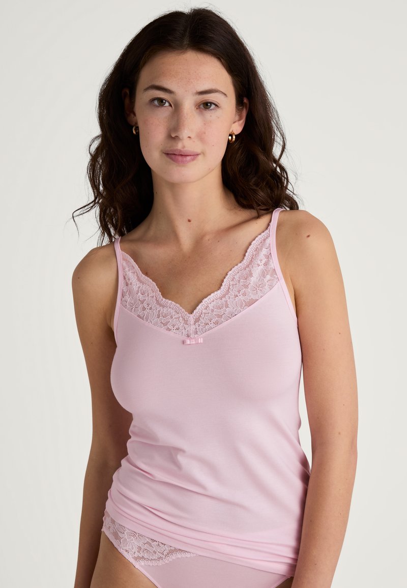 Light pink camisole featuring a floral lace neckline and a small pink bow accent, with thin straps and a soft, smooth texture.