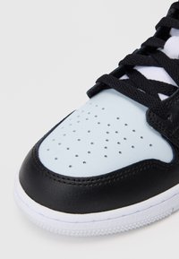 Czarne skórzane trampki z jasnoniebieskim perforowanym noskiem, czarnymi sznurowadłami i białą gumową podeszwą. Posiadają gładkie i teksturowane powierzchnie.