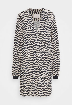 Sukienka w wzory z długimi rękawami, kołnierzykiem w kształcie litery V oraz abstrakcyjnym wzorem w kolorach granatowym i kremowym. Posiada luźny krój i miękką teksturę materiału.