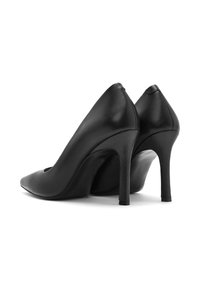 Tacchi alti in pelle nera con punta appuntita e sottile tacco a stiletto. Texture liscia con un design elegante e minimale.
