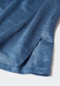 Modrá lněná tkanina, detailní pohled, s jemnou texturou a subtilním tkaním, s bočním rozparkem na lemu.