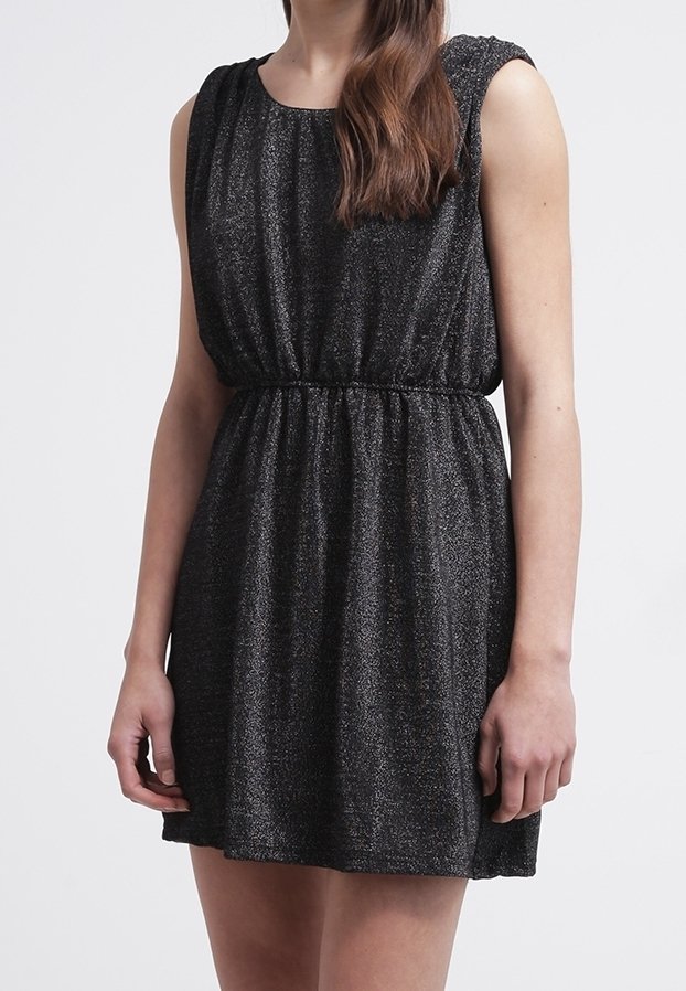 Robe noire sans manches pailletée avec une taille froncée, portée par une personne debout devant un fond clair uni.