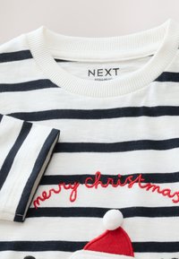 Langærmet skjorte med striber i hvid og marineblå, med "glædelig jul" broderet i rødt og et filt nissehue-detalje med kvast.