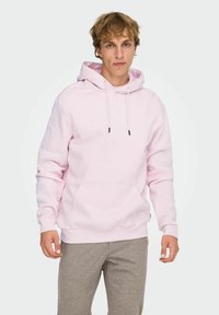 Felpa con cappuccio rosa chiaro in tessuto morbido, con tasca frontale, coulisse regolabili e polsini e orlo a coste.