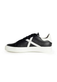 Sneaker in pelle nera con suola in gomma bianca e un distintivo design a croce bianca sul lato. Superficie testurizzata, forma della punta rotonda.
