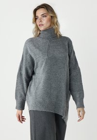 Szary sweter z golfem, wykonany z miękkiej, teksturowanej dzianiny, o luźnym kroju, z opadającymi ramionami i asymetrycznym wykończeniem dołu.