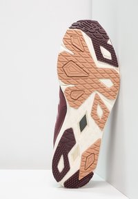 Sportovní bota s maroon horní částí, gumovou podrážkou s geometrickými vzory a kontrastním světlým tan akcentem.