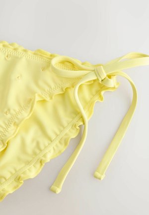 Geel bikini onderstuk met rimpelranden, striksluiting en een gestructureerd oppervlak met kleine geborduurde details. Zacht, rekbaar materiaal.