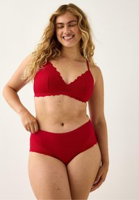 Rød lingeri sæt bestående af en bralette med blonderkanter og scallop-kant samt højtaljede trusser med blonderdetaljer. Glat tekstur.
