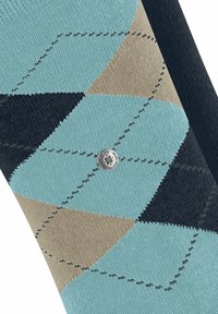 Teksturowana tkanina z geometrycznym wzorem w jasnoniebieskie, beżowe i ciemnoniebieskie diamenty, z srebrnym guzikiem z logo w pobliżu centrum.