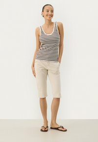 Brun og hvid stribet tanktop, lys beige knælange shorts, båret med brune flip-flops. Glat stof, afslappet pasform, minimal detaljering.