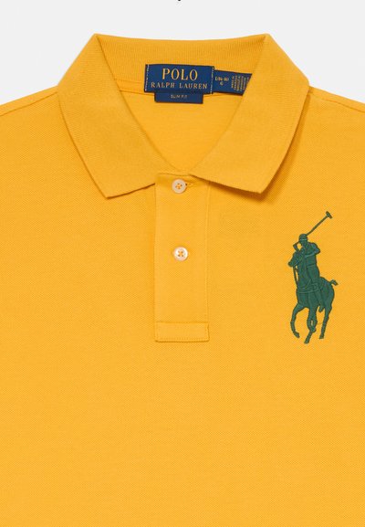 Rumena polo majica iz teksturiranega bombaža. Ima zeleno vezeno logo podobe igralca poloja in dve gumbni zaponki. Oblikovana je v slim fit slogu.