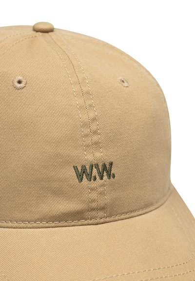 Beigenvärinen puuvillainen baseball-lippalakki, jossa etupaneelissa tummanvihreä kirjailtu "W.W."-logo ja ommellut tuuletusreiät.