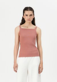 Ribbed, fitted tank top in dusty rose, featuring wide straps and a squared neckline. Pairing with flowy white pants enhances simplicity.