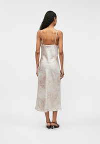 Σατέν midi φόρεμα, ανοιχτό μπεζ με διακριτικό animal print, λεπτές ρυθμιζόμενες τιράν τες και εφαρμοστό σχήμα, που τελειώνει στο μεσαίο μέρος της γάμπας.